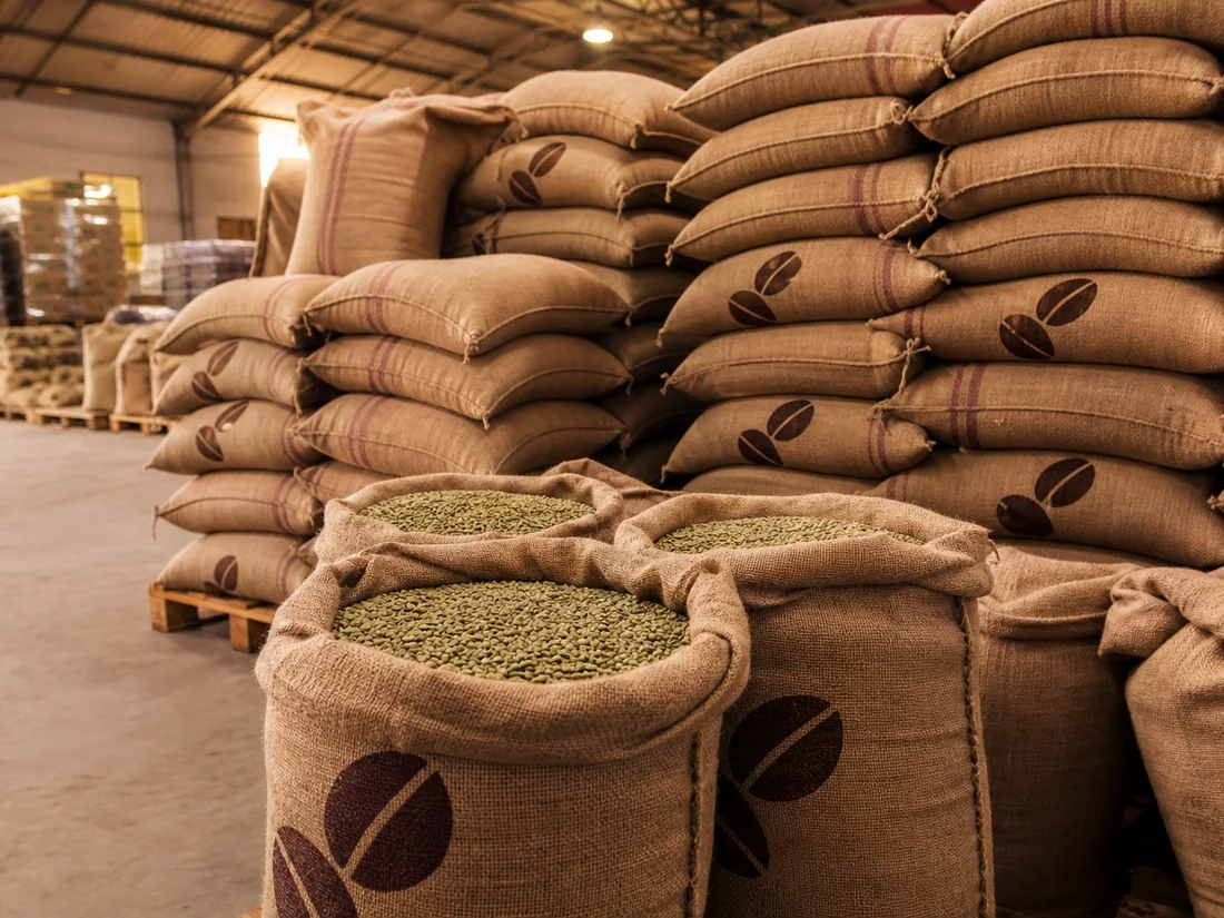Stacked jute export bags of Colombian green coffee in a warehouse